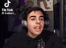 a young man wearing headphones is making a funny face in front of a camera .