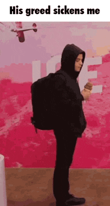 a man in a hooded jacket is holding an ice cream cone .