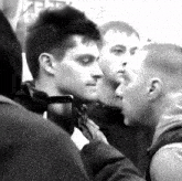 a group of young men are standing in a crowd and one of them has a cell phone in his hand