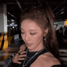 a close up of a woman 's face with a ponytail and a necklace