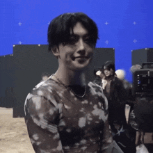 a man wearing a tie dye shirt is standing in front of a blue screen