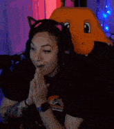 a woman wearing headphones and a cat ear headband is sitting next to a stuffed animal