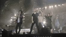 a group of people standing on a stage with the letter d in the lower right corner
