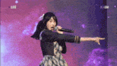 a girl is singing into a microphone while pointing at the camera .