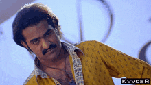 a man with a mustache is wearing a yellow shirt that says kvvcsr on it