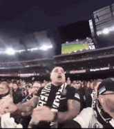 a man wearing a pennsylvania scarf stands in a crowd of people