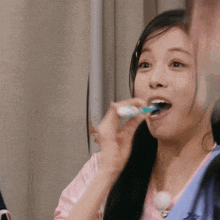 a woman is brushing her teeth with a toothbrush .