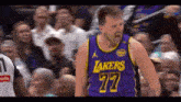 a basketball player for the lakers is standing in front of a crowd .