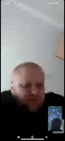 a man with a beard is on a video call on a cell phone .