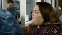 a woman is sitting in front of a refrigerator and looking at a man .