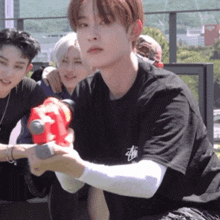 a man in a black stussy shirt holds a red water gun