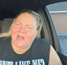 a woman in a car wearing a shirt that says " damn i love me "