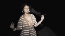 a woman in a striped dress is standing in the dark and dancing .