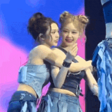 two women are hugging each other on a stage and one of them is smiling .