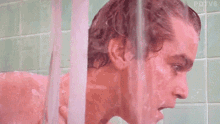 a man is taking a shower in a bathroom with a shower curtain behind him .