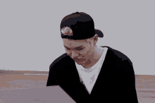 a young man wearing a black hat and a white shirt is looking at a piece of paper