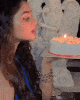 a woman is blowing out a candle on a cake