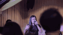 a woman sings into a microphone in front of a crowd of people