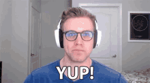 a man wearing headphones and glasses says yup !