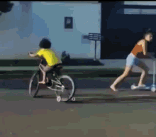 a woman is pushing a scooter while a boy rides a bike