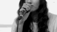 a black and white photo of a woman singing into a microphone