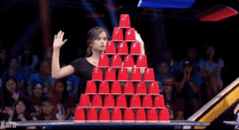 a woman stands in front of a pyramid of red cups with the word kara in the corner
