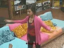 a woman in a pink cardigan stands in front of a couch