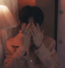 a man with a ring on his finger covers his face with his hands