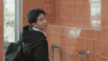 a man with a backpack stands in a bathroom