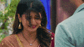 a woman wearing a black necklace and earrings is crying