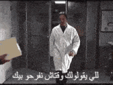 a man in a white lab coat is walking through a doorway holding a piece of paper .