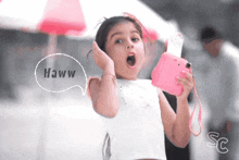 a little girl is holding a pink camera and says haww