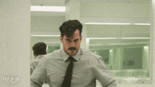 a man in a suit and tie is standing in front of a window that says tom cruise m.i.6 on it