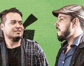 two men standing next to each other with a green screen in the background