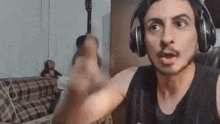 a man wearing headphones is making a funny face while sitting at a table in a living room .
