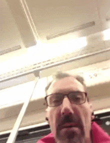 a man with glasses and a beard is taking a selfie on a bus .