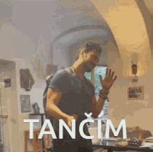 a man is dancing in a room with the word tancim in white
