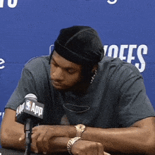 a man sitting in front of a microphone with the nba app logo on it