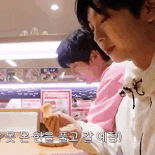 two men are sitting at a table eating food .