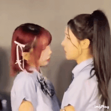 two girls are standing next to each other and kissing each other .