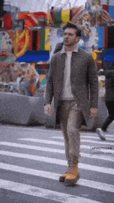 a man in a coat is walking across a crosswalk in a city .