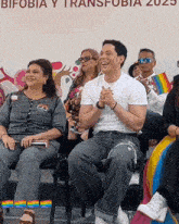 a group of people sit in front of a sign that says bifobia y transfobia
