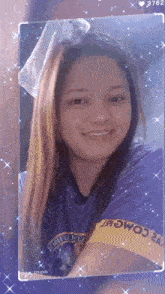 a woman wearing a purple shirt that says ' comm ' on the sleeve