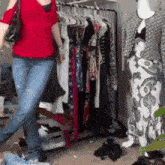 a woman in a red shirt is standing in front of a clothes rack