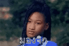 a girl in a blue shirt is making a funny face in a blurry photo with foreign writing on it .