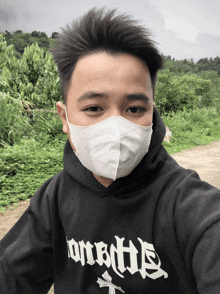 a man wearing a face mask and a black hoodie that says onebitle