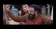 a man with a beard is standing next to a woman and holding his fist up in the air .
