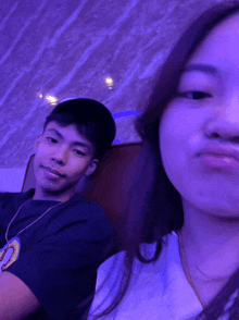 a man and a woman are posing for a picture with a purple background