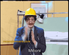 a man wearing a hard hat applauds in front of a screen that says ' milioni ' on it