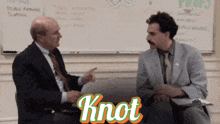 two men are sitting in front of a whiteboard and the word knot is on the bottom